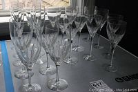 Photos show a collection of 20 Lenox Crystal Firelight pattern glasses arranged in rows on a table by a window with natural light. Various glass types such as water glasses, champagne flutes, and small wine glasses are visible, all clear crystal with cut designs.
