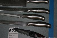 Top view of Farberware knives showing serrated and smooth blades with stainless steel handles and one black handled serrated utility knife