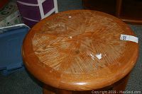 Top close-up of round wooden end table showing woven/patterned wood grain finish