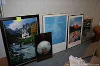 Wide view showing all five framed prints arranged on floor, displaying varying landscape and city themed artwork.