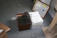 Set of white binders in boxes, brown file drawer, black wire organizers and pen holder on carpet