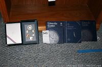 Full view of the coin collection including the Prestige set and three Lincoln Cent albums.