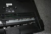 Close-up photo of the back of the TV showing various input ports including HDMI, component, and audio connections, with Dynex branding visible.