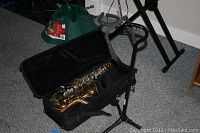Alto saxophone in open soft case on adjustable tripod stand on carpeted floor