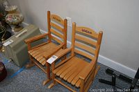 Two wooden children's rocking chairs side by side, one with 'Zachary' in green on the backrest and another with 'Logan' in black, showing armrests, slatted seat and back design.