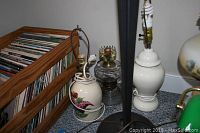 Photo showing several lamps including white ceramic lamps, a vintage glass oil lamp, and part of a floor lamp.
