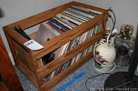 Wooden crate holding several vinyl record albums from various artists.