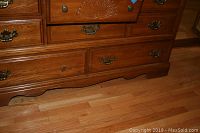 Close-up of dresser base showing metal drawer handles and carved decoration on front drawer.