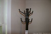 Photo of black metal hall tree coat rack with multiple double hooks, shown next to beige wall and window