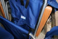 Close-up clear photo showing blue fabric seat and backrest with small GCI Outdoor logo tag, metal frame, and wooden armrest.
