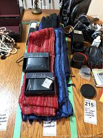 Two black leather Club Rochelier wallets in original boxes, stacked on folded scarves with gloves and umbrellas visible nearby.