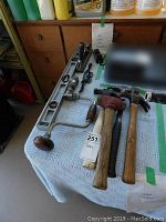 Photo showing the six tools including 3 hammers, 2 Stanley planes, and a metal level on a white towel.