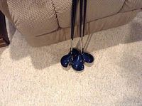 Four golf clubs leaning on a couch with blue heads and metallic shafts