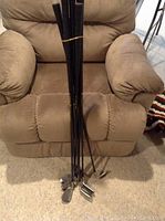 Full set of 8 golf irons with black grips, steel shafts in a recliner chair.