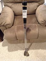 Photo of three Ausmac golf wedges standing on a beige textured fabric armchair, showing the full length of shafts and grips.