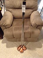 Four Tiger golf clubs placed together against a cushioned chair showcasing the shafts and handles.
