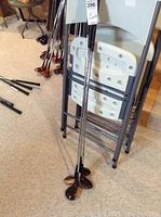 Photo displaying four MacGregor golf clubs leaning against a folded chair, showing metal shafts and wood heads.
