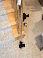 Three Ping golf clubs leaning against stairs. Clubs have metal shafts and wood heads.