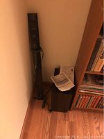 Photo showing the tall tower speaker and the subwoofer placed on the floor in a corner near shelving.