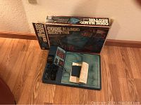 Photo of Code Name Sector game box, unfolded game board with electronic unit, cables, and instructions laid out on floor.