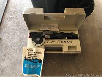 DYMO 1011 Tapewriter inside beige plastic carrying case with instruction manual partially visible.