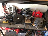 Full shelf showing various power tools including jig saw, toting base, large saw, clamps