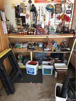 Wide view of the workbench showing assorted tools on top and pegboard behind, plus buckets and other containers below