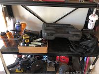 Shelf with various tools including clamps, containers of small parts, rubber gloves, and other tools.
