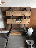 Front view of Black & Decker Workmate portable work center showing wooden jaws with holes and general wear, attached to a metal frame base.