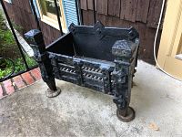 Front and side view of cast iron fireplace insert showing ornate details and slatted grate base