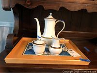 Full set of bone china coffee tea set on wooden tray with blue decorative mat inside tray