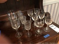Front view of assorted glassware on wood surface showing variety of etched and clear glasses