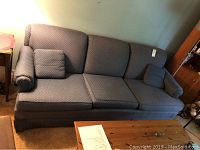 Full couch showing three seat cushions and two throw pillows, set in a living room environment