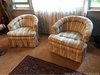 Two club chairs placed side by side by a window with beige, pink, and blue striped fabric upholstery with visible stains and marks.