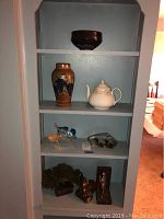 Photo of shelving display with the glass birds vase, Wedgewood teapot, decorative vases, bookends, and additional decorative items.