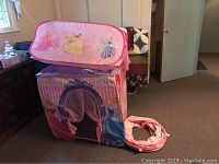 Pink princess-themed play tent set up in room with images of Disney princesses and castle entrance curtain.