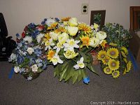 Photo showing various artificial floral arrangements featuring daisies and other colorful flowers in baskets and pots.