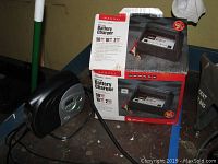 Photo showing Schumacher Signature Series battery charger box on a shelf with charger unit beside it.