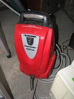 Red Husky powerwasher with 1550 PSI label and black handle on top, viewed from front with visible power cord.