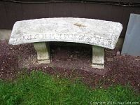 White cement griffon bench viewed from above showing the textured top and weathered surface with chips and discoloration, resting on two ornately carved pedestal legs.