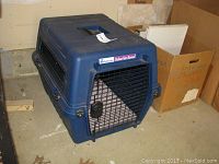 Blue Petmate Deluxe Vari Kennel plastic pet carrier, view from side and top showing ventilation and door mechanism.