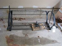 Image showing the entire metal pot rack, including side arches and horizontal bars, with some hooks placed on a board inside the rack.