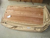 Cedar closet panel with beige canvas cover laid flat, showing wood grain and metal fasteners along edge.