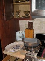 Kitchen counter with Pfaltzgraff platter, three stacked baking pans, and wooden knife block with four knives