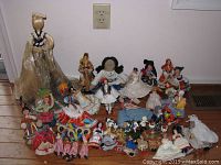 Photo of a large assortment of dolls from different countries arranged on the floor, showing their traditional costumes and diverse styles.