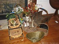Photo showing multiple artificial floral arrangements and an assortment of woven baskets grouped together near a fireplace and a floor area.