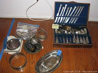 Overall view of flatware in wooden case with additional serving dishes on floor beneath