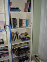 Wide view of white shelving with assorted books organized mostly upright and some stacked horizontally