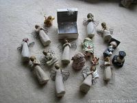 Overview of all angel figures and worry box with other small decorative figurines on carpeted floor.