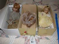 Two vintage dolls in separate cardboard boxes with a vintage wig in plastic bag in center box